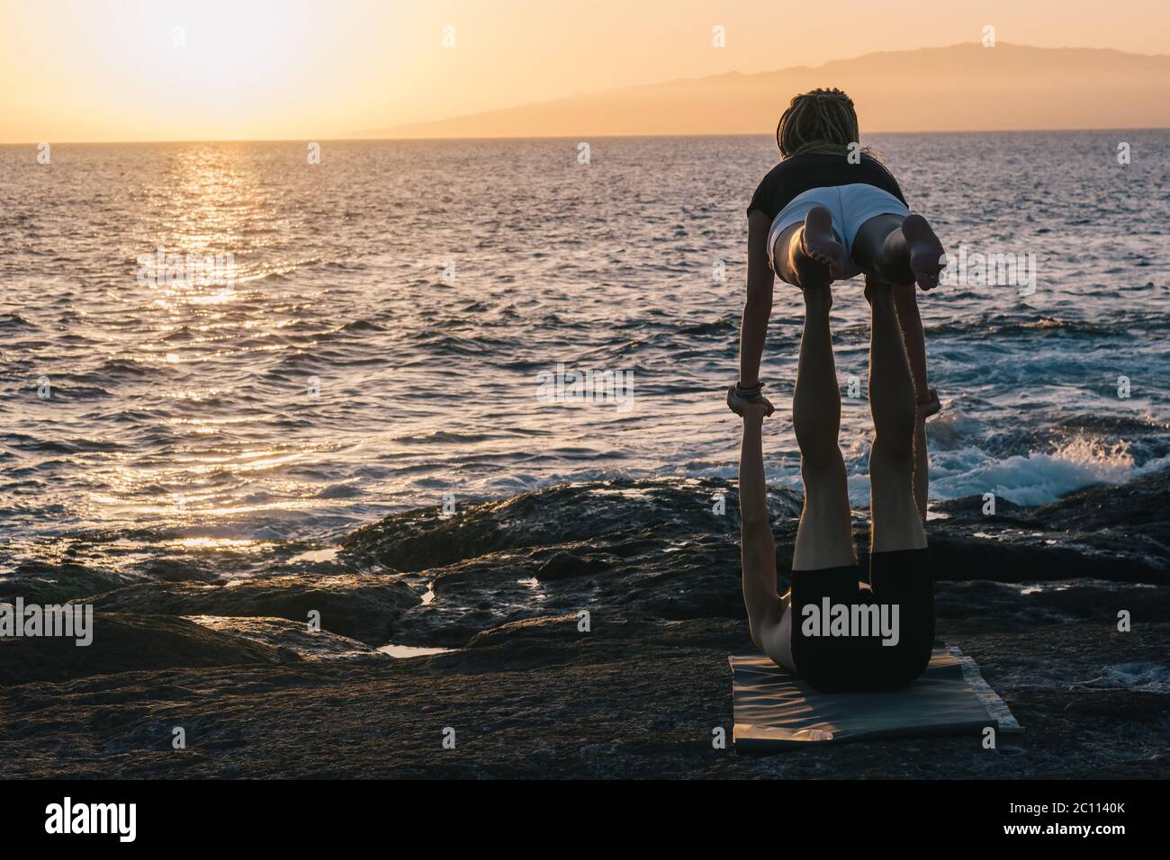 coppia facendo esercizi di yoga all'aperto in spiaggia Foto Stock