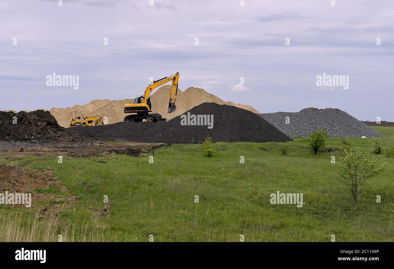 Escavatore giallo lavorando a scavare nella cava di sabbia Foto Stock