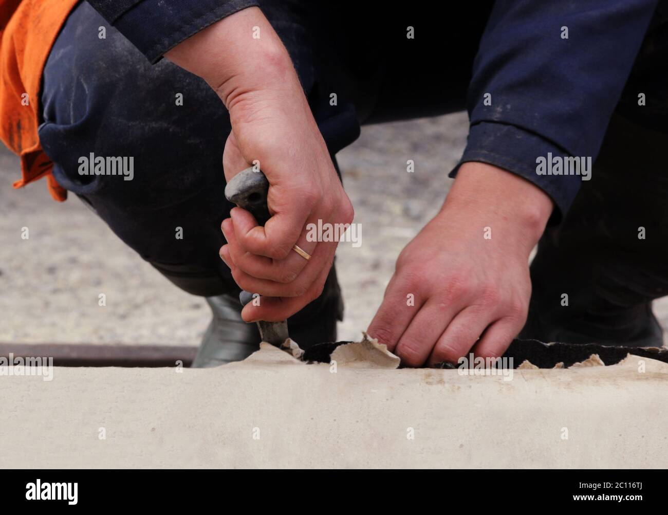 i lavoratori stanno tagliando i pezzi da un rotolo di materiale di copertura per lavori di riparazione impermeabilizzanti per mantenere l'acqua . Foto Stock