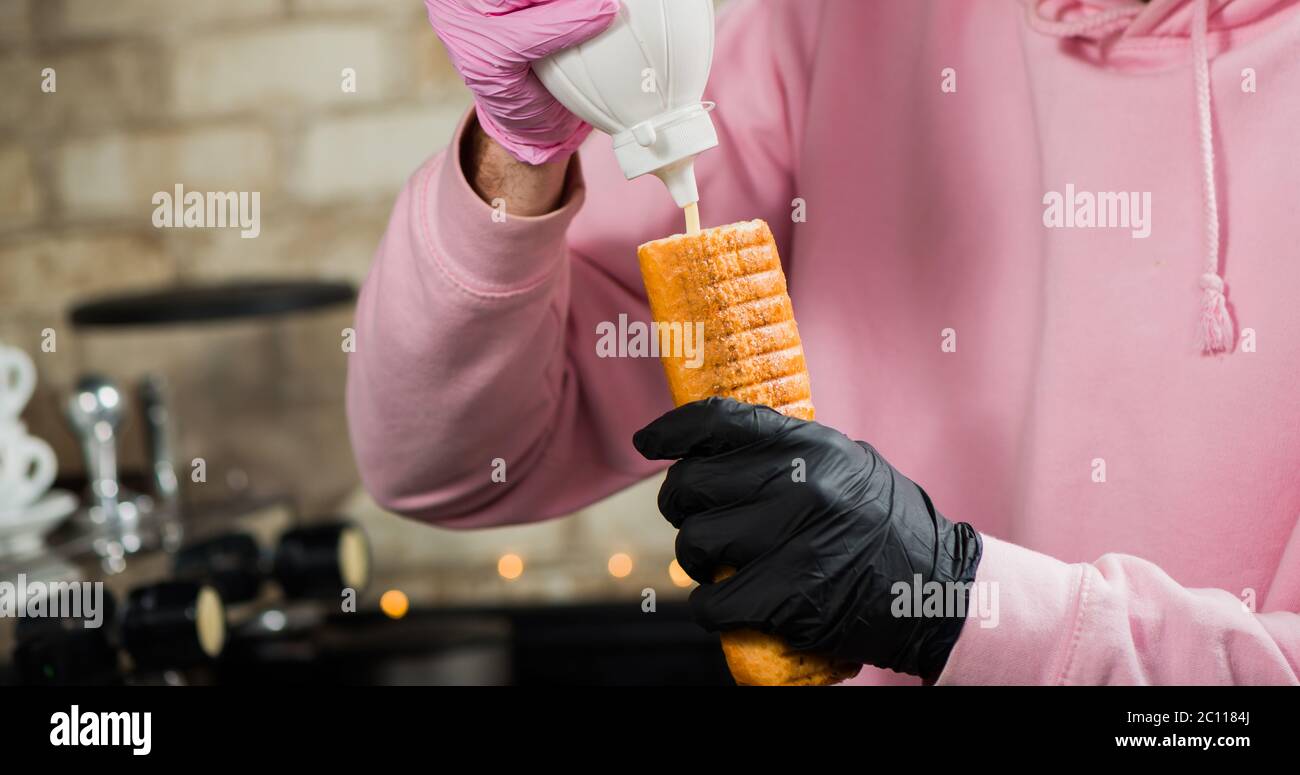 barista aggiungendo salsa in rotolo francese di cane caldo Foto Stock