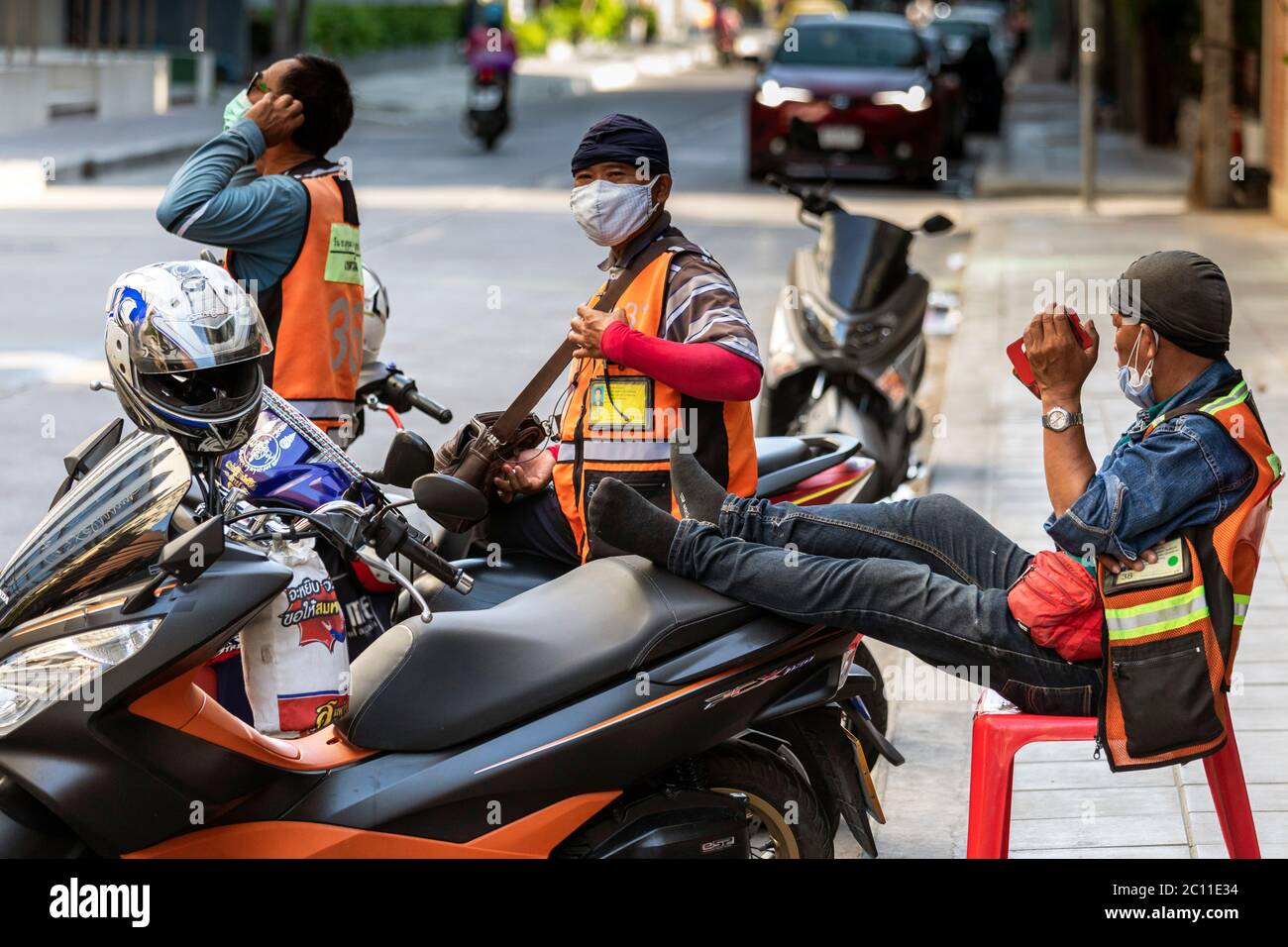 I conducenti di taxi motociclistici con maschere che aspettano i clienti durante la pandemia di Covid, Bangkok, Thailandia Foto Stock