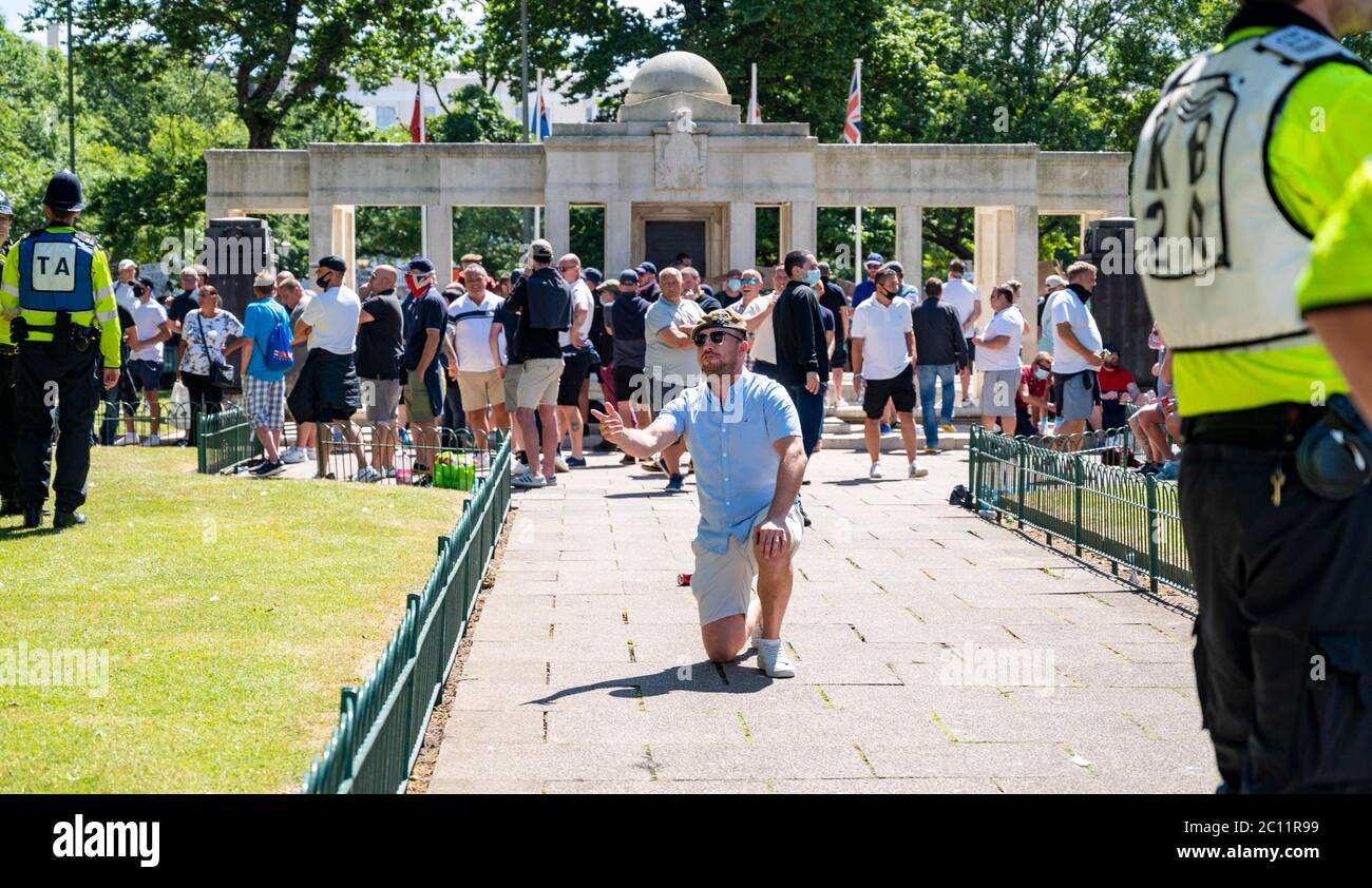 Brighton UK 13 giugno 2020 - uno degli uomini creduto di far parte di gruppi di destra scende al ginocchio al memoriale di guerra, mentre al memoriale di guerra migliaia di persone prendono parte al raduno di protesta contro il razzismo Black Lives Matter attraverso Brighton Today . Ci sono state proteste in tutta America , Gran Bretagna e altri paesi dalla morte di George Floyd mentre è stato arrestato dalla polizia a Minneapolis il 25 maggio : Credit Simon Dack / Alamy Live News Foto Stock