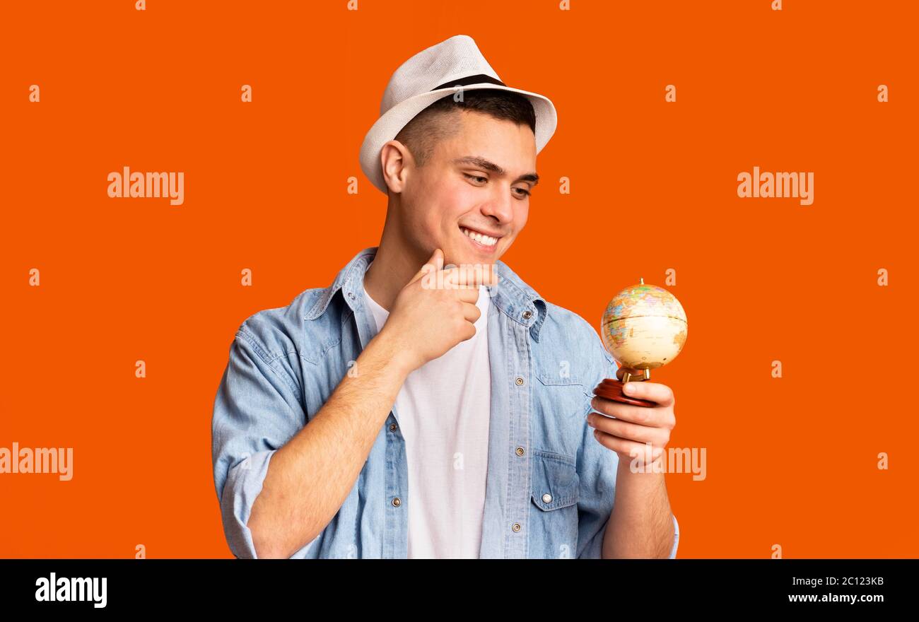 Turista che tiene piccolo globo, cercando dove andare Foto Stock