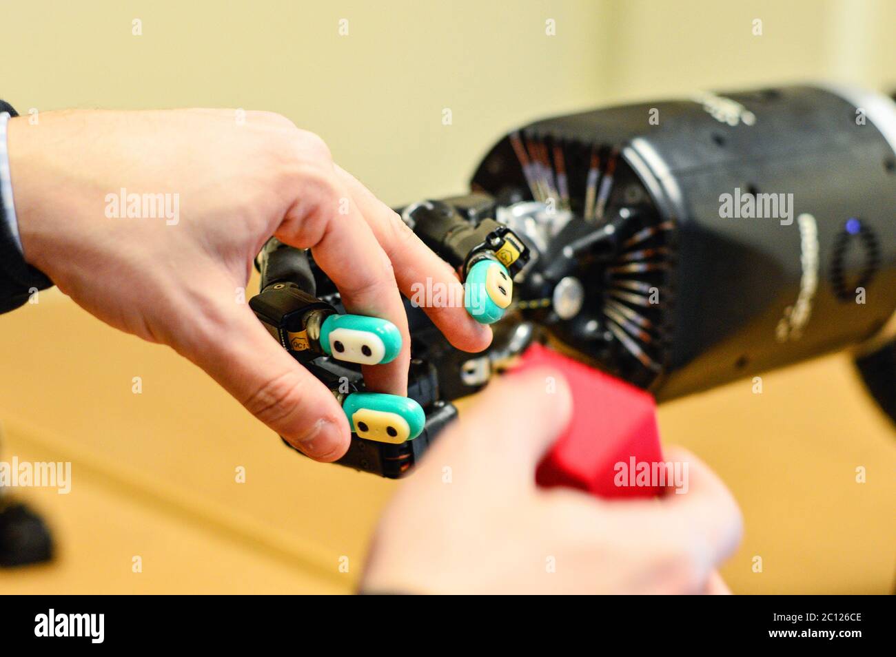 L'uomo lascia la mano del robot per tenere un cubo rosso nel laboratorio di ricerca. Foto Stock