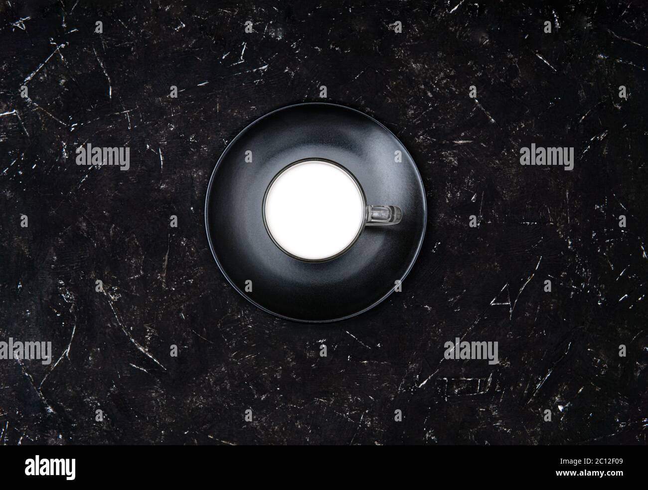 Bicchiere di latte su un piatto nero opaco su fondo nero testurizzato. Vista dall'alto, spazio di copia. Latte per il concetto di perdita di peso. Foto Stock