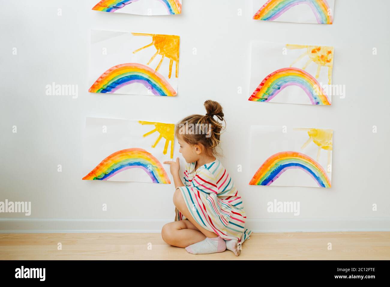 Bambina che indica uno dei dipinti arcobaleno inferiore sulla parete Foto Stock