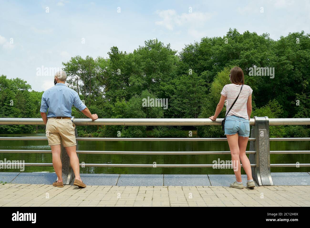 Un uomo calvo e una donna che gode la vista del fiume mantenendo la distanza a pochi metri per evitare la diffusione del coronavirus. Foto Stock