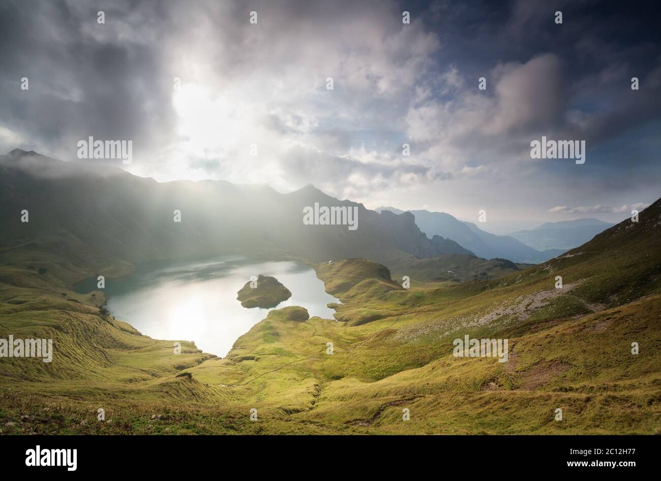 luce del sole attraverso le nuvole sopra il lago alpino Foto Stock