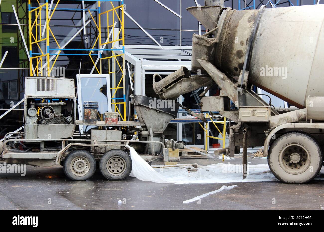 pompa e miscelatore per calcestruzzo per lavorare insieme versando pavimenti in cemento nel centro commerciale per la riparazione. Foto Stock