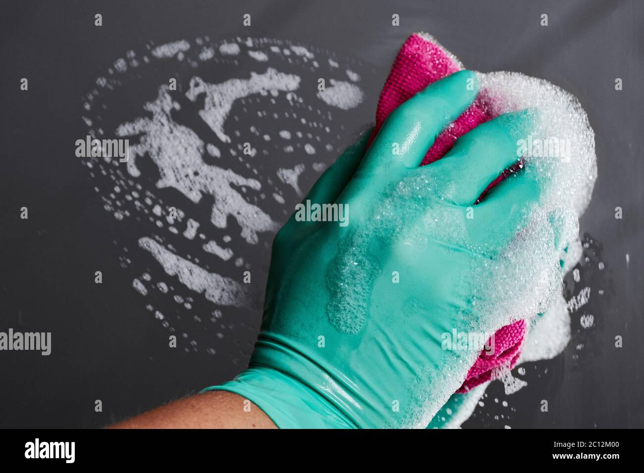 Primo piano della mano femminile con guanto e specchio per la pulizia in microfibra e rimozione di polvere e sporcizia Foto Stock