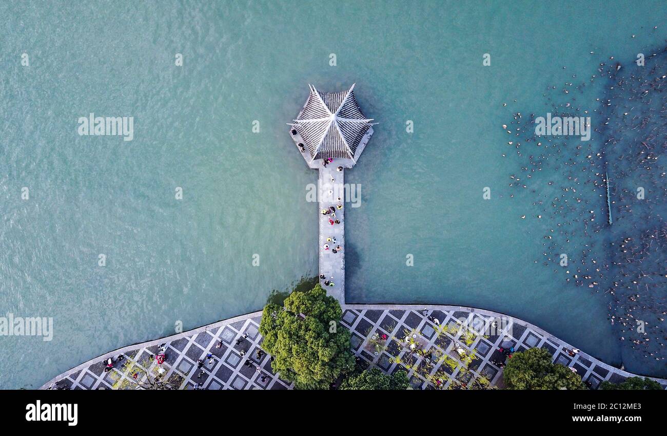 Vista aerea dall'alto sulla piccola pagoda cinese presso il lago blu con persone che camminano su un ponte che conduce alla pagoda. Foto Stock