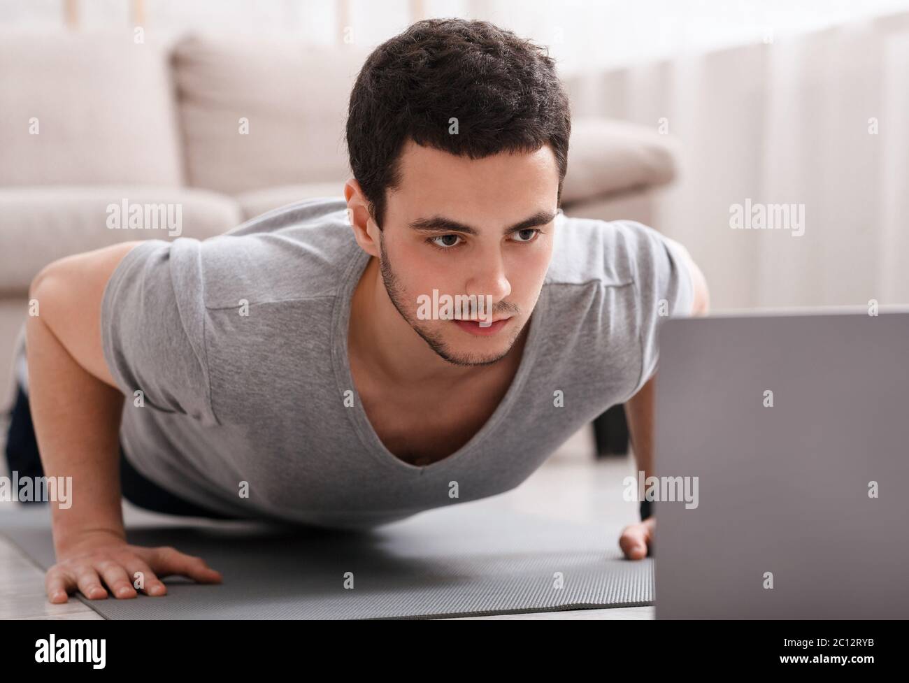 Lavoro remoto e sport online. Guy è spingere e guardare il notebook all'interno Foto Stock