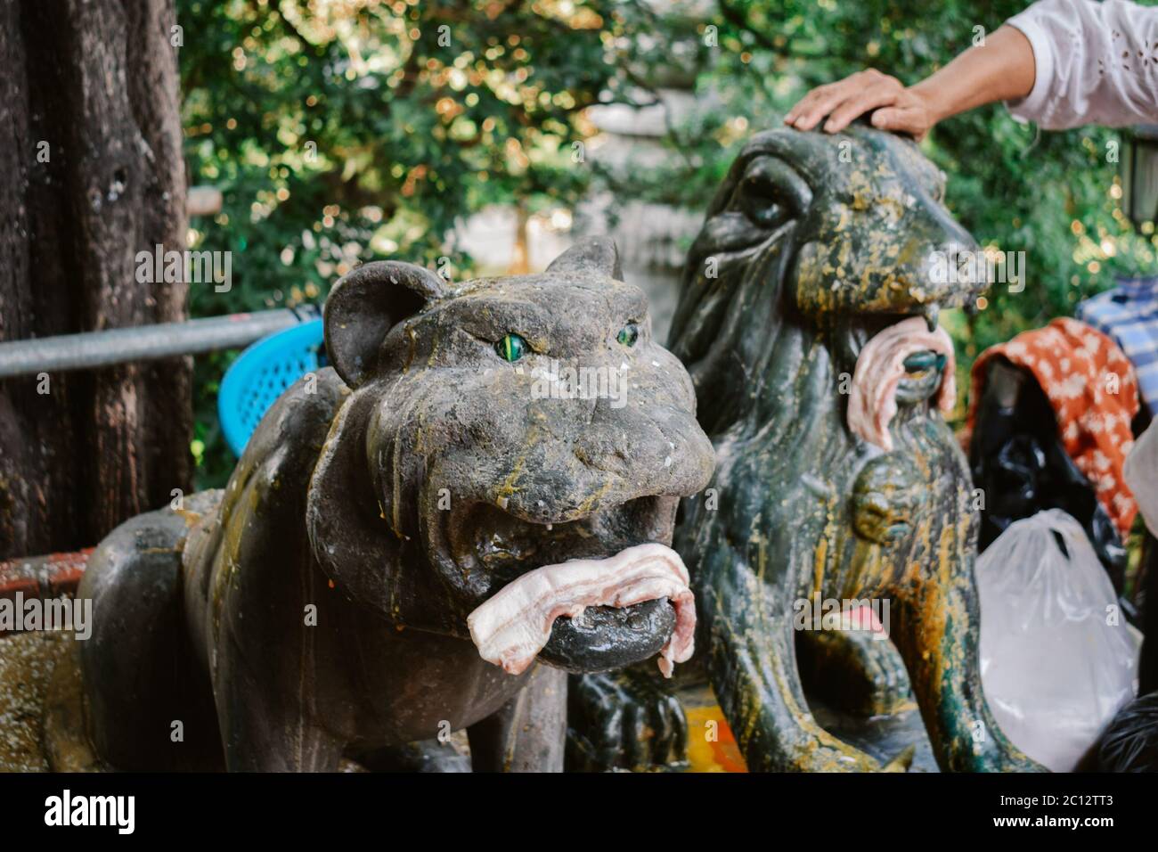Statue di tigri e leoni con prosciutto sacrificali doni da adoratori nel tempio di Wat Phnom a Phnom Penh Cambogia Foto Stock