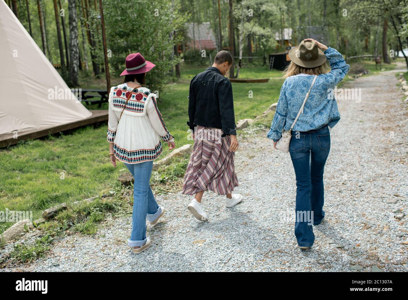Vista posteriore dei giovani che camminano sul campeggio festival godendo di bel tempo Foto Stock