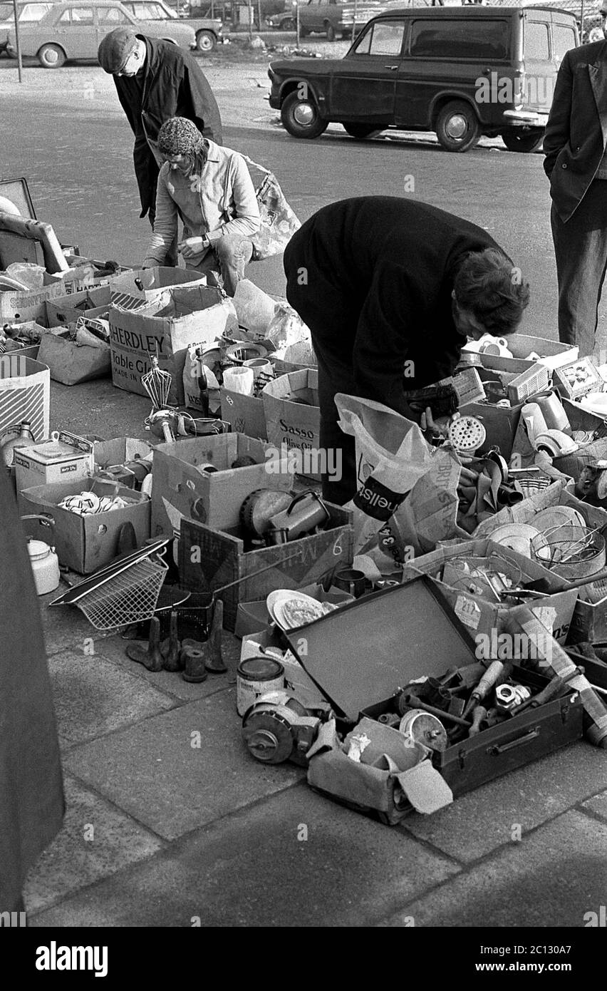 AJAXNETPHOTO. 27 FEBBRAIO 1975. PORTSMOUTH, INGHILTERRA. - MERCATO DELLE PULCI - IN STRADA UNICORN; BUYER RUMMAGE ATTRAVERSO I BENI USATI E VESTITI SPARSI SUL PAVEMENT.PHOTO:JONATHAN EASTLAND/AJAX REF:7513 19 134 Foto Stock