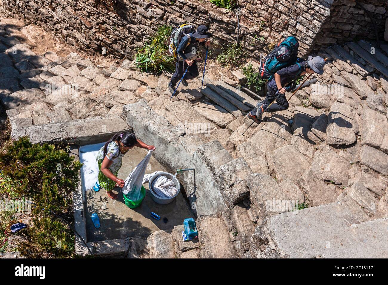 Pokhara, Nepal - Gennaio 2011: Donna che lava vestiti ed escursionisti nel villaggio di montagna Foto Stock