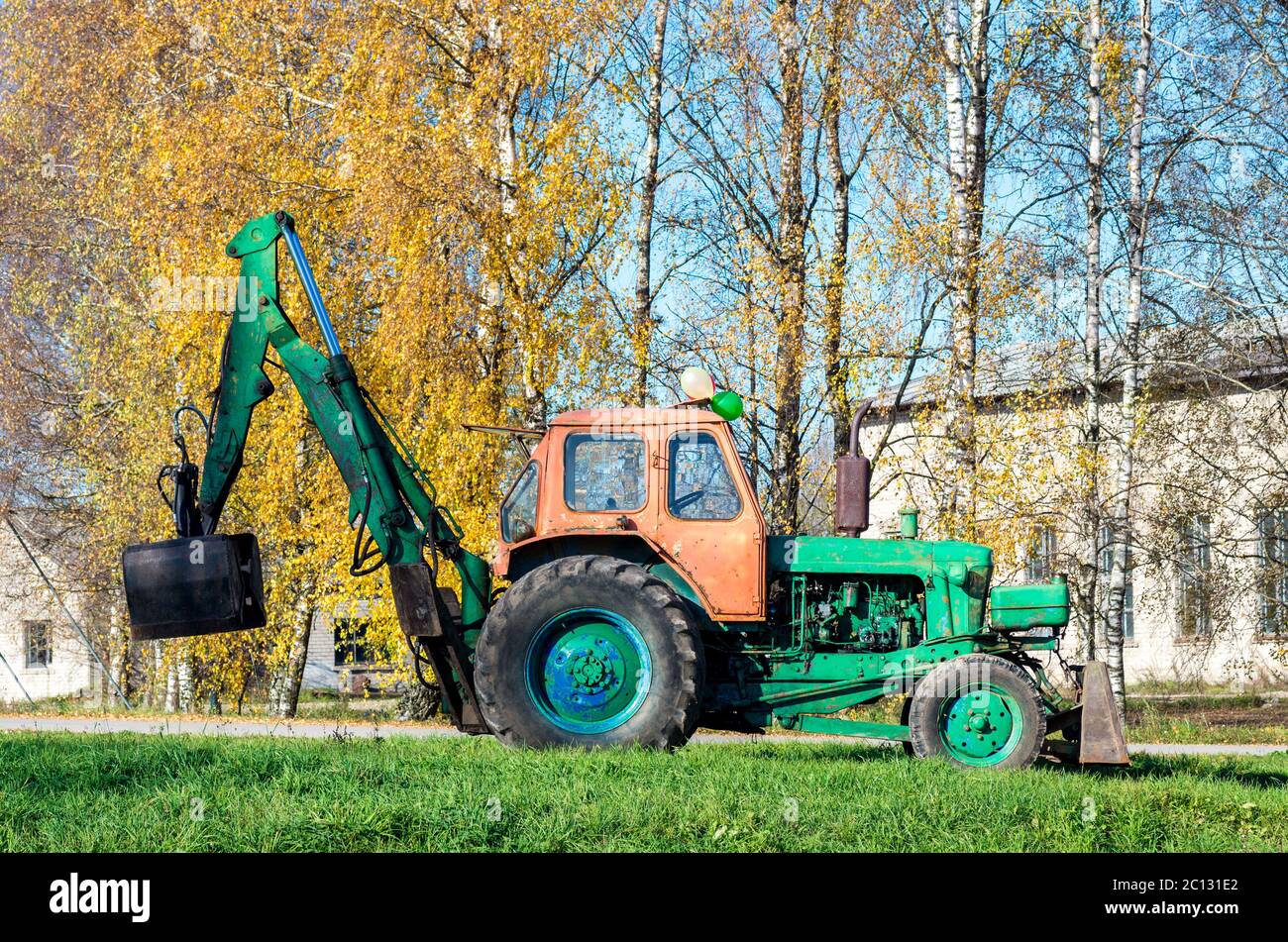 Russo vecchio trattore con caricatore a sinistra gli alberi Foto Stock