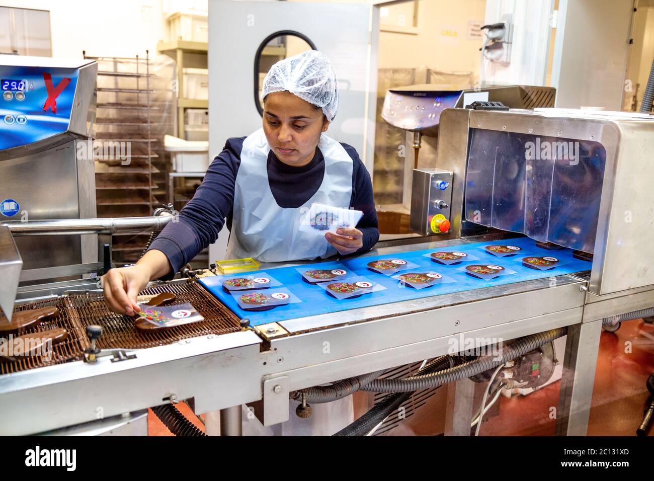 Lavoratore di fabbrica di cioccolato che mette motivi colorati su barrette di cioccolato, l'Atelier du Chocolat, Musée du Chocolat (Museo del cioccolato) Bayonne, Francia Foto Stock
