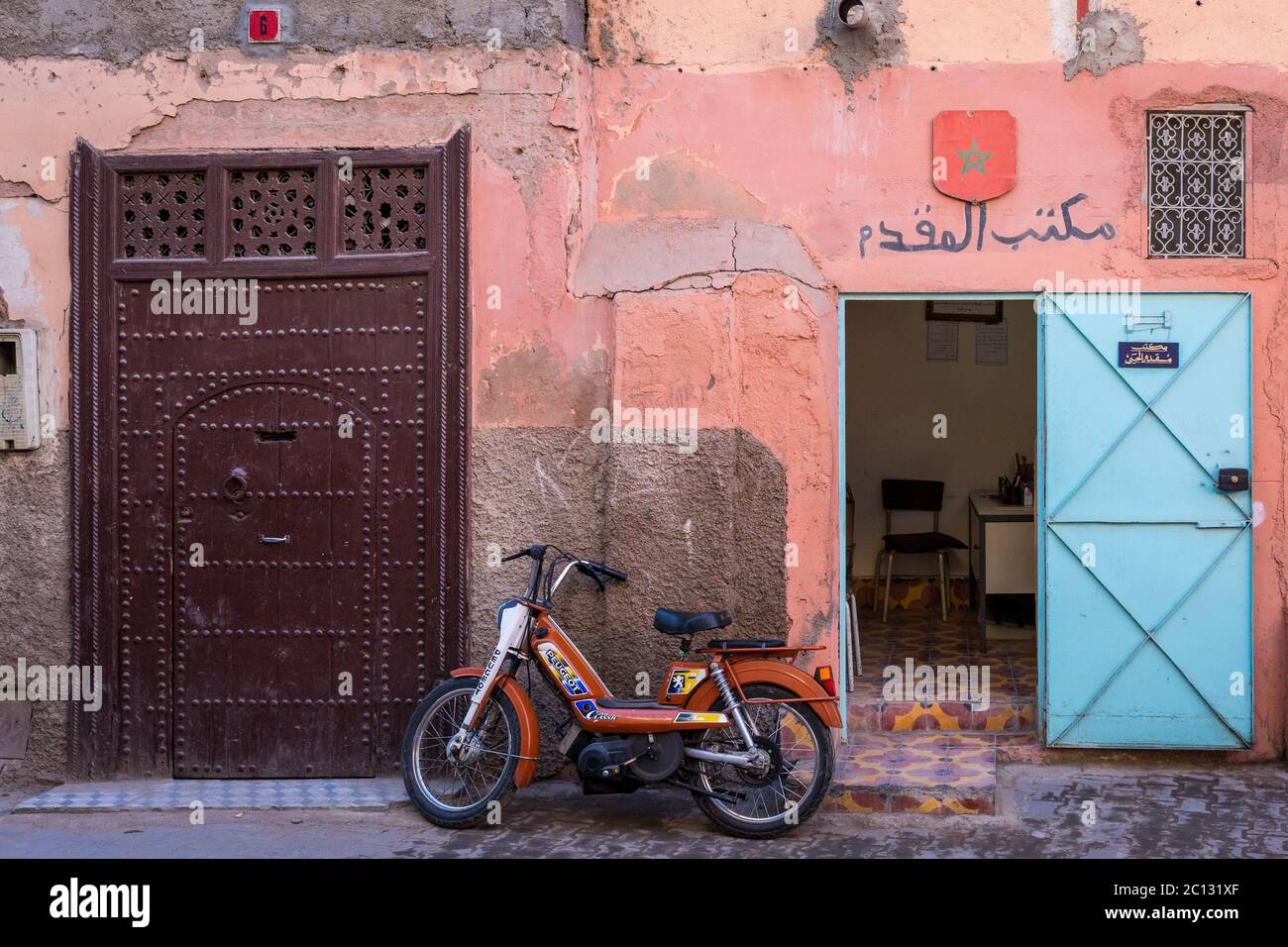 Vista sulla città di Marrakech, con un muro rosa e moto parcheggiata in strada Foto Stock