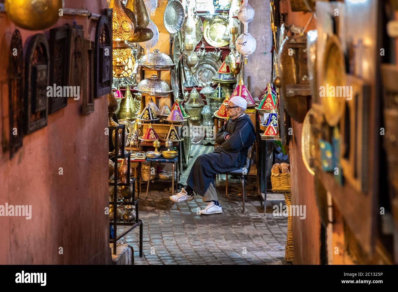 Marrakech, Marocco: Un vicolo stretto all'interno della medina con negozi o souk che vendono illuminazione e oggetti di arredamento per la casa illuminati Foto Stock