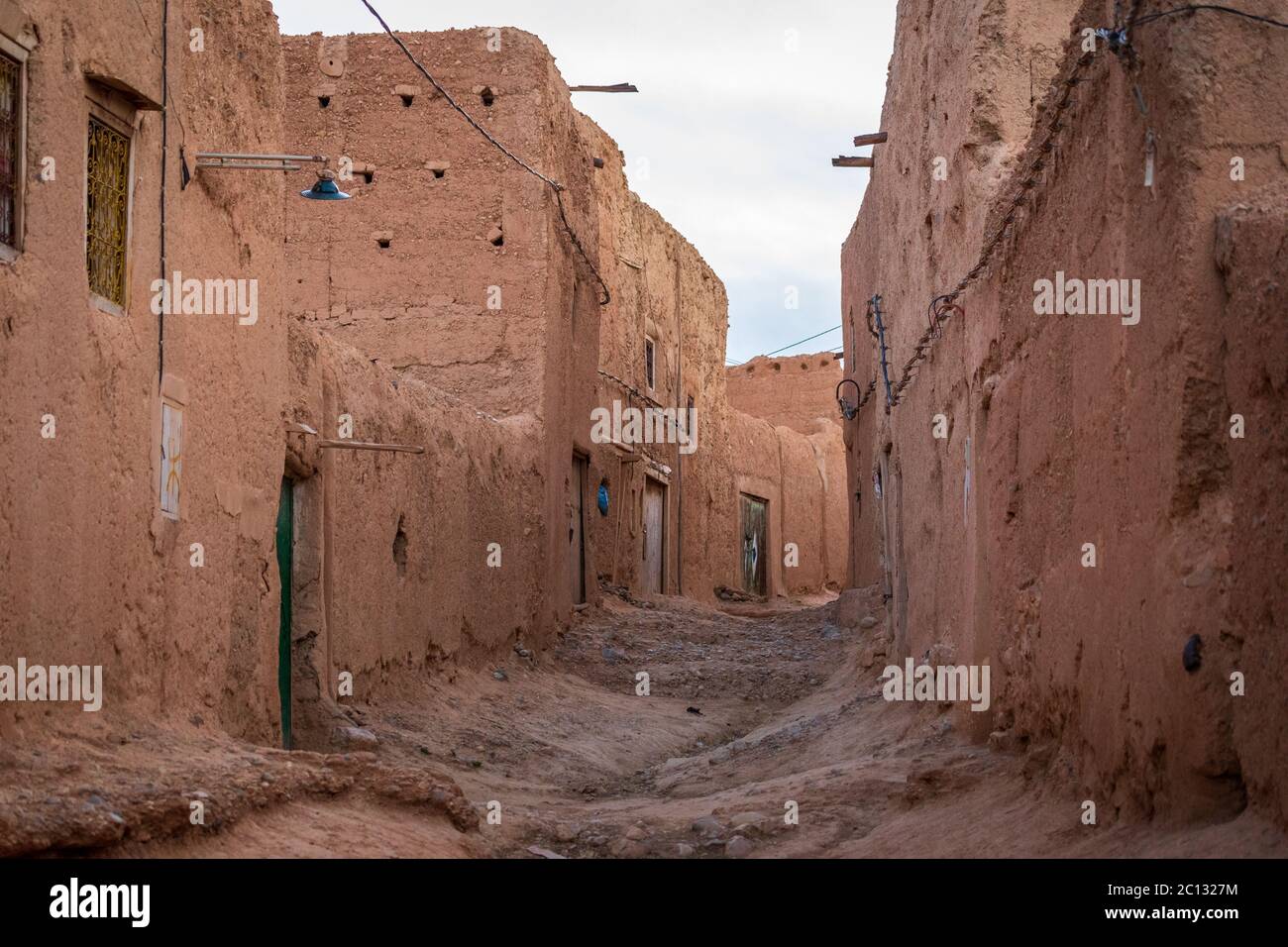 Una strada vuota con muri in mattoni di fango in un semplice villaggio berbero nella provincia di midelt, marocco Foto Stock