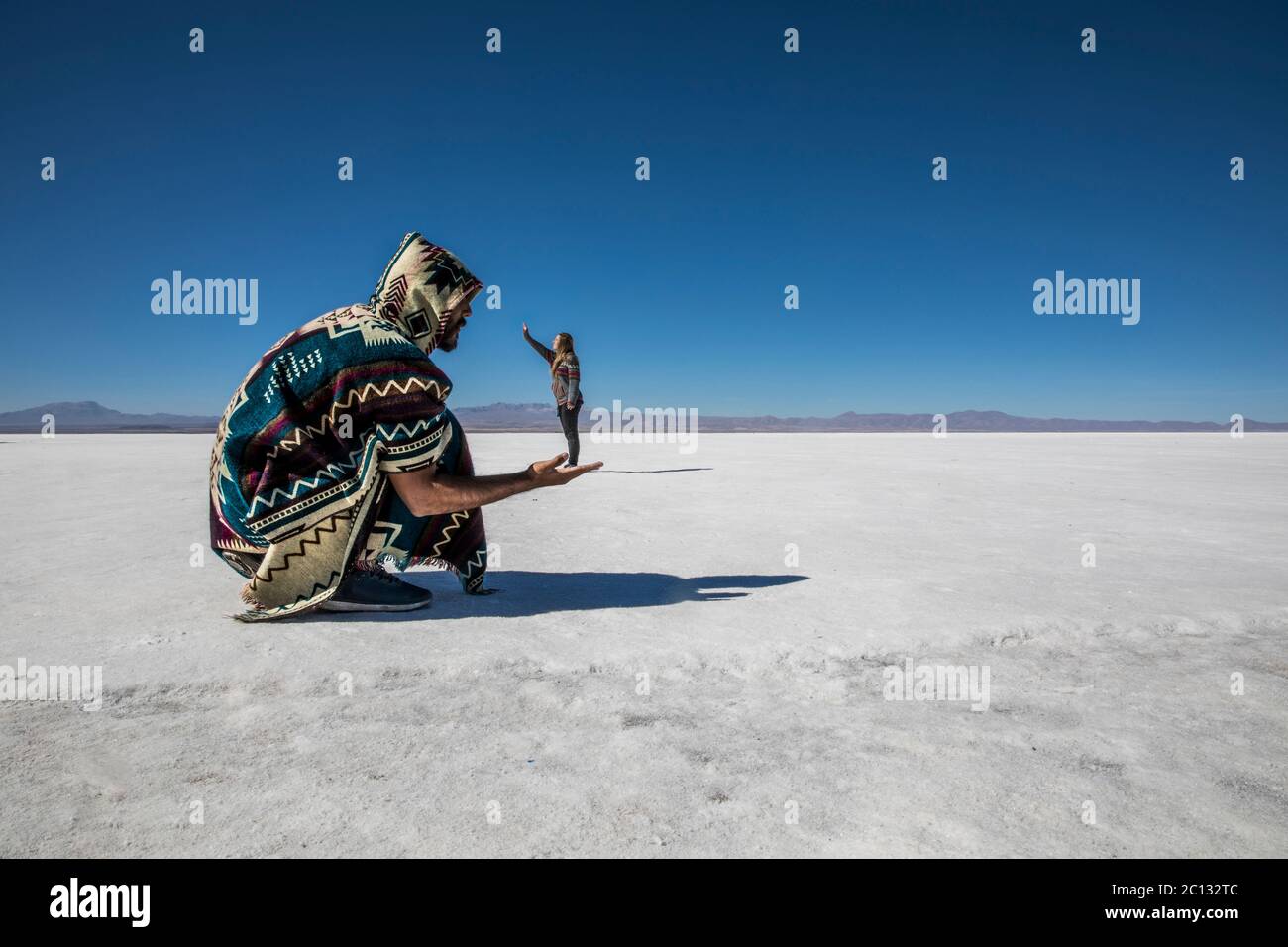 Coppia che gioca nelle saline del deserto, divertendosi con la prospettiva Foto Stock