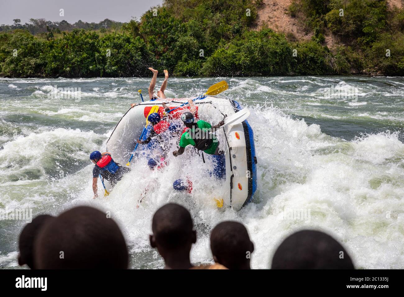 Gli spettatori guardano come un'acqua di whlte zattera durante una spedizione di rafting sulle rapide sul fiume Nilo vicino a Jinja, Uganda, Africa Foto Stock