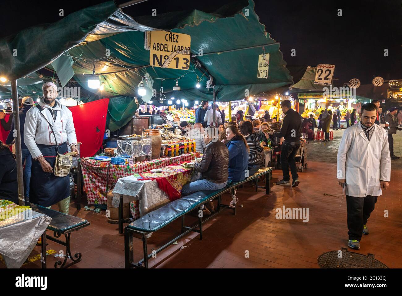 Bancarelle di cibo all'aperto di strada che cucinano e servono cibo nella piazza principale di Place Djemaa El Fna a Marrakech, Marocco, di notte Foto Stock