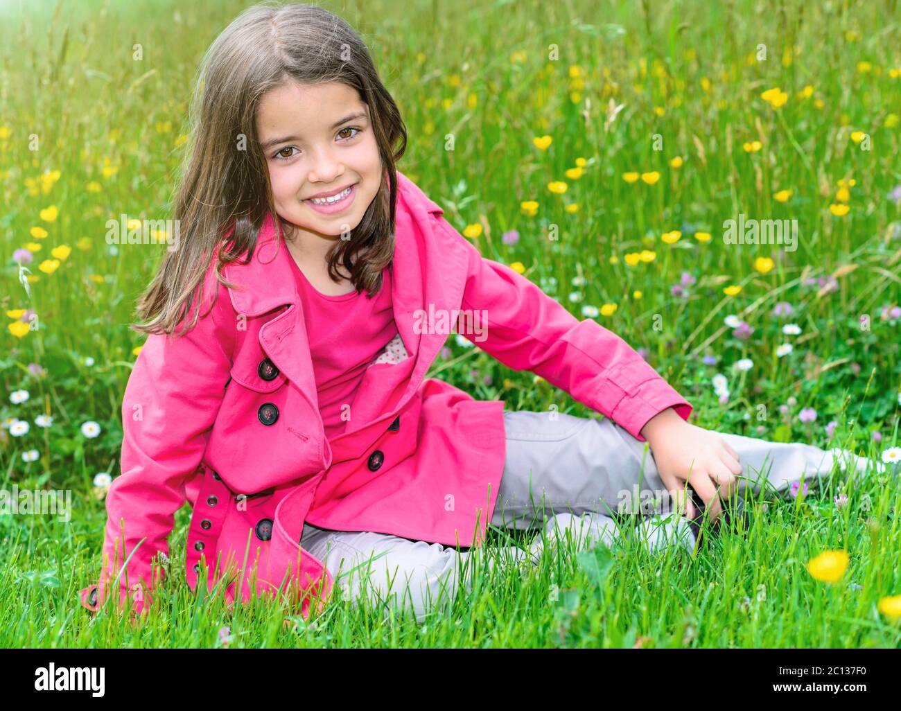 felice bambino carino seduto in un'erba di un giardino di fiori Foto Stock