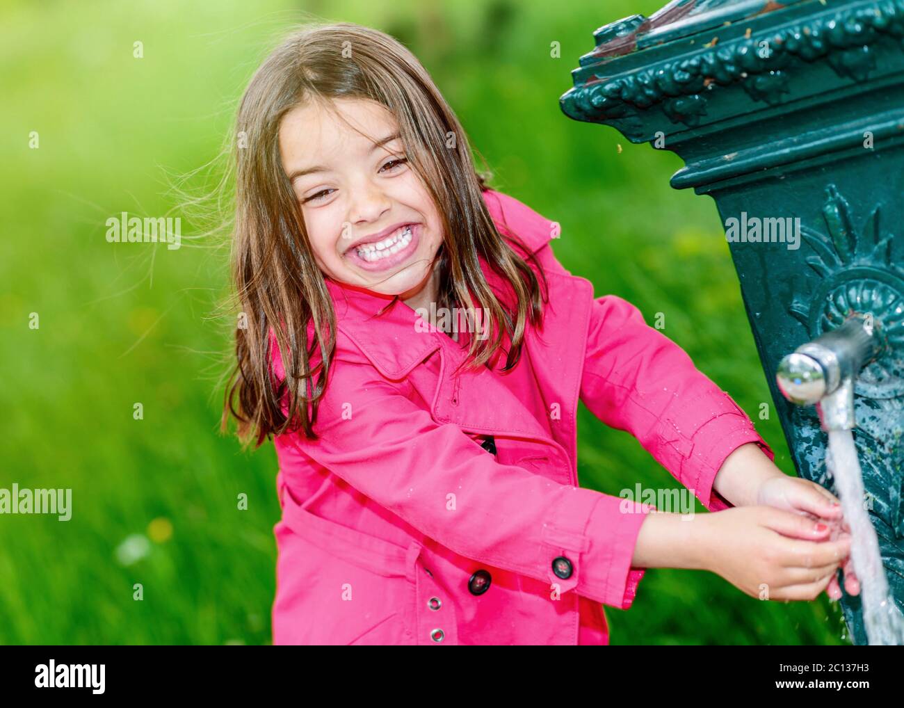 Bambina che beve acqua in una fontana Foto Stock
