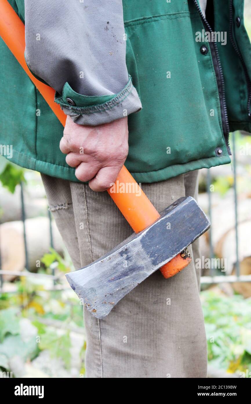ascia pesante con manico arancione in mano agli uomini di lavoro. Foto Stock