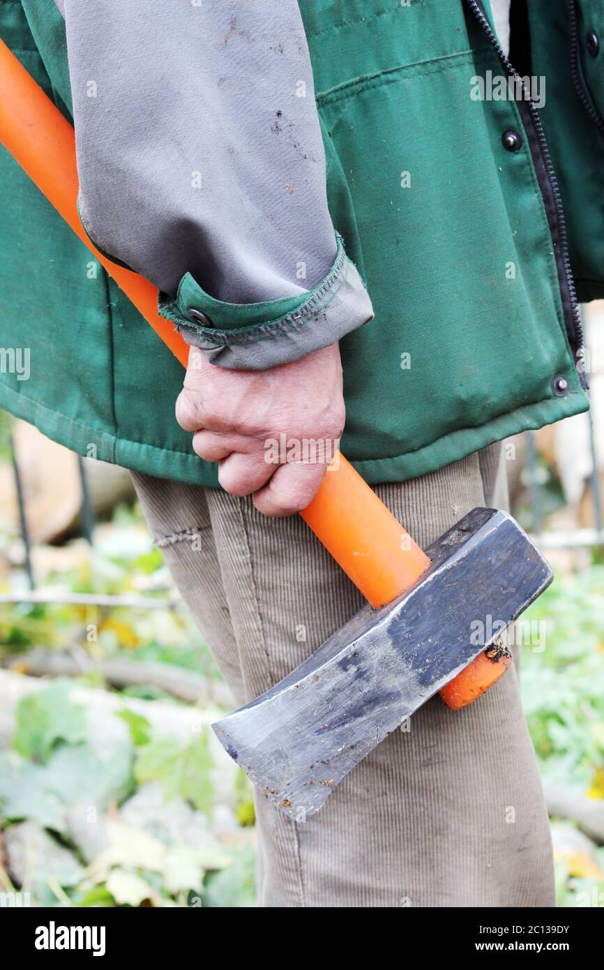 ascia pesante con manico arancione in mano agli uomini di lavoro. Foto Stock