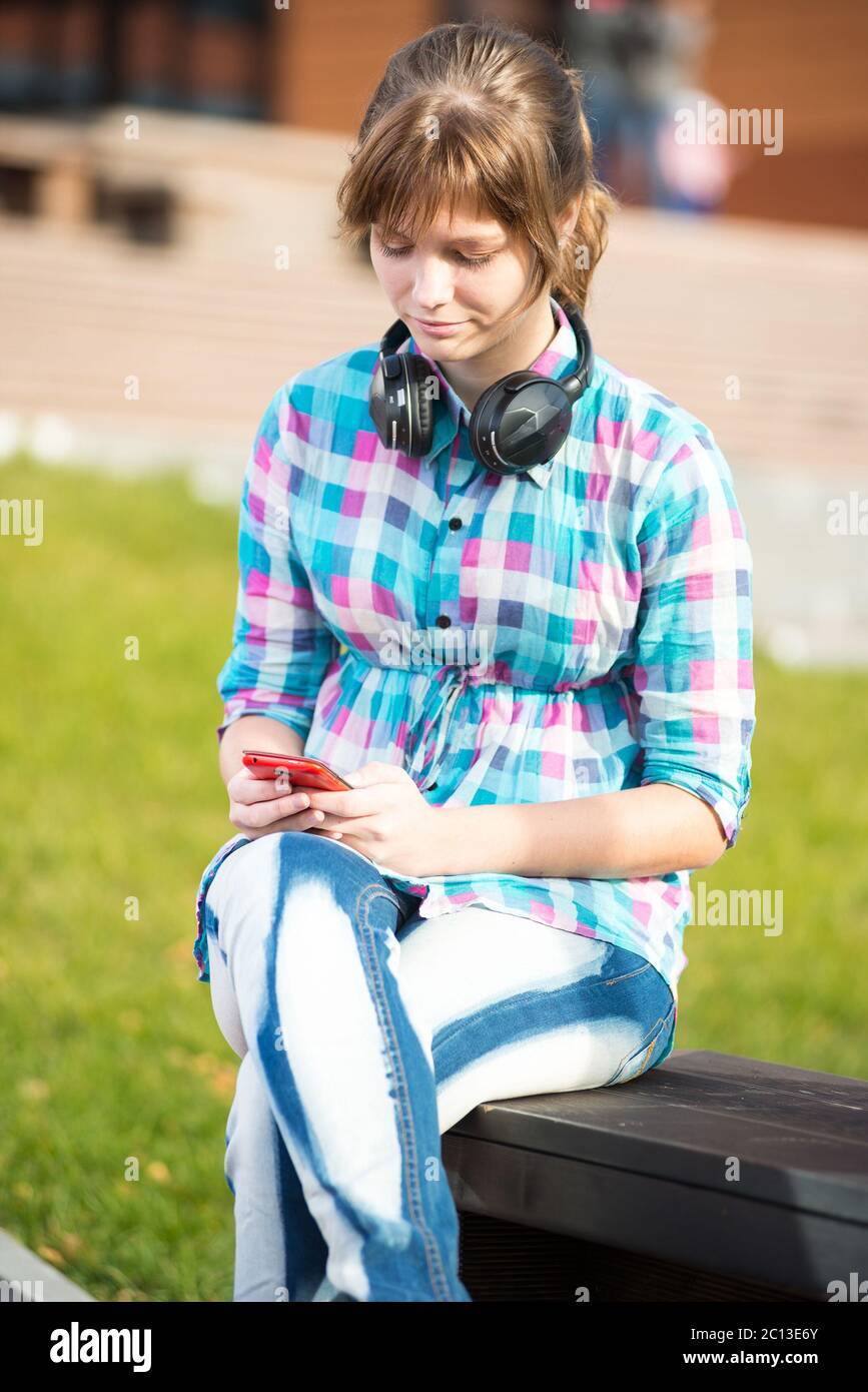 Sorridente giovane studentessa scrivere messaggi su un telefono cellulare. Campus Foto Stock