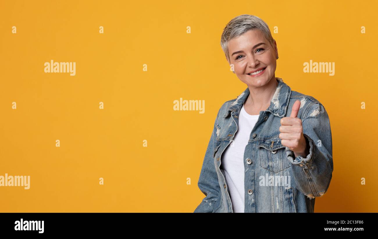 Buona promozione. Sorridente mature Lady gesturing Thumb Up alla fotocamera Foto Stock