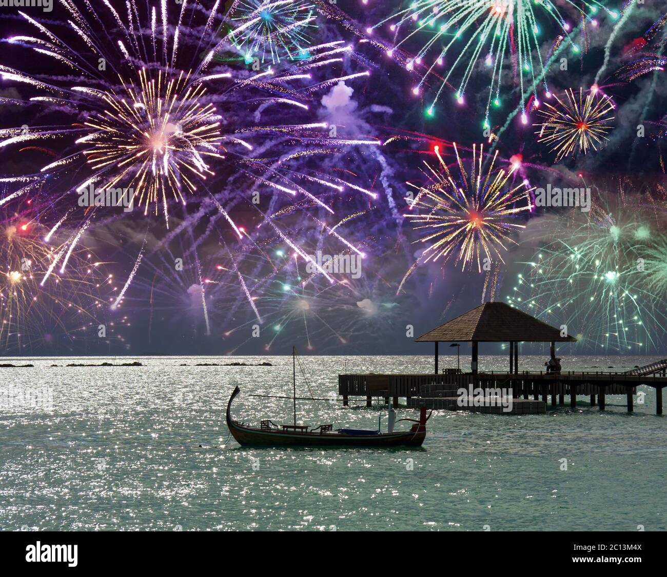 Fuochi d'artificio festosi sul mare e una silhouette barca sull'acqua. Maldive. Foto Stock