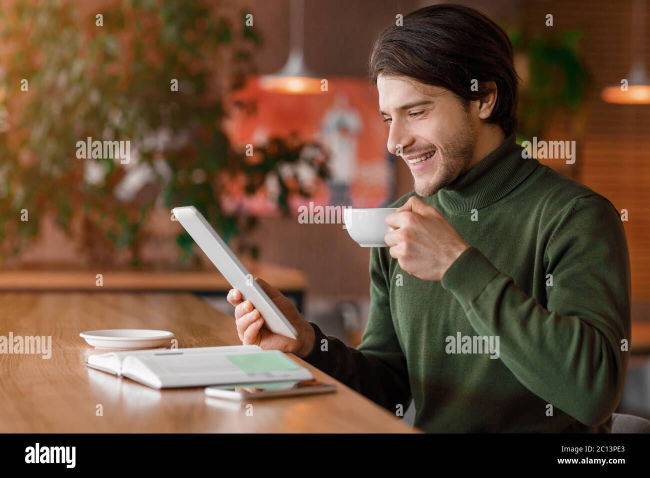 Uomo d'affari felice di leggere notizie mentre beve il caffè del mattino Foto Stock