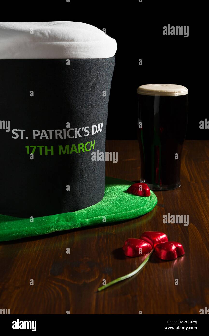 St Patrick giornata con una pinta di birra nera, cappello e shamrock su una tavola Foto Stock