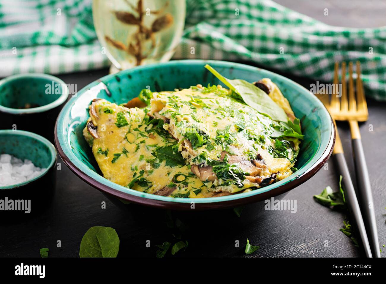 Spinaci e frittata di funghi. Frittata composta da uova, funghi e spinaci. Cucina italiana. Foto Stock