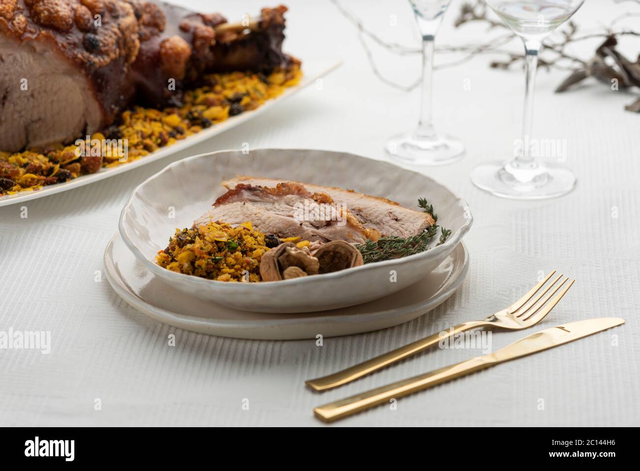 fette di prosciutto arrosto di maiale con noci su un piatto bianco e cibo su sfondo Foto Stock