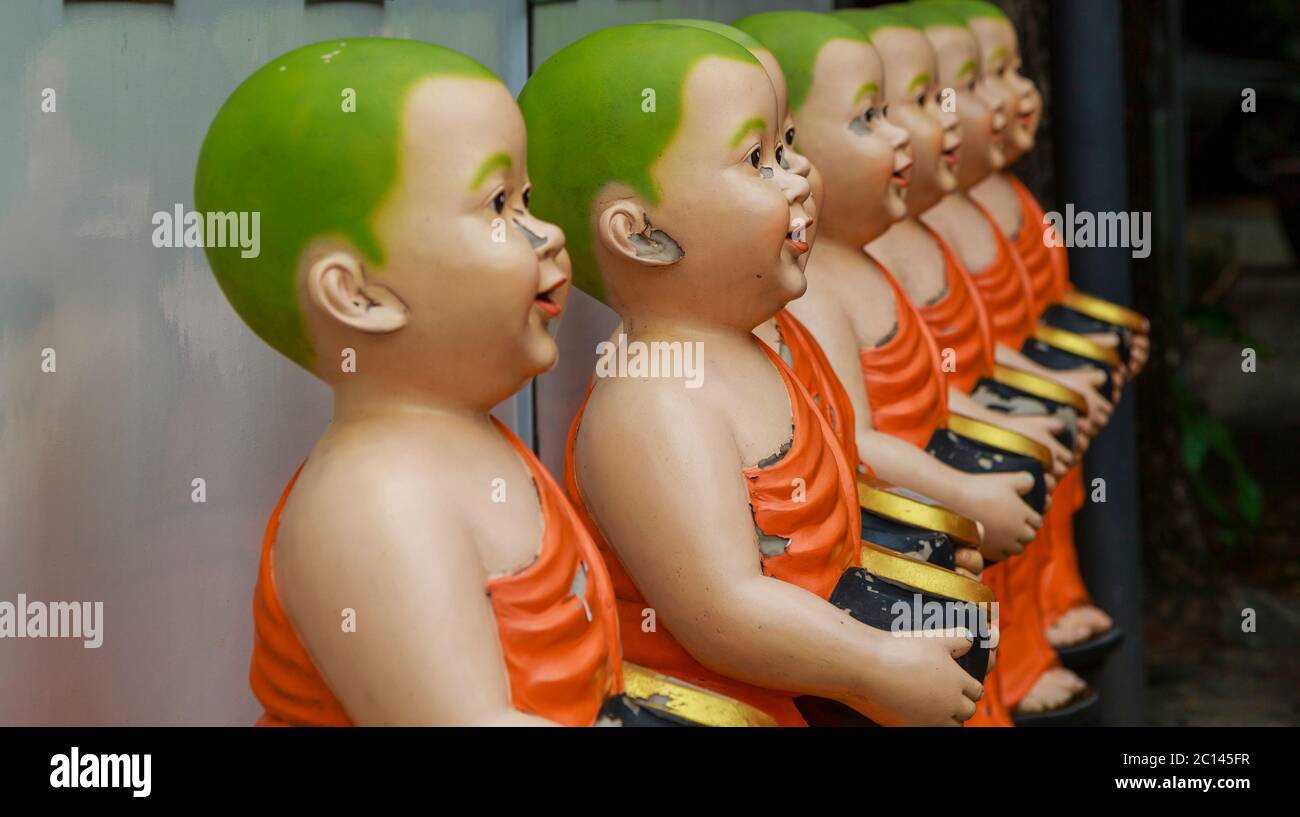 Bambini come statue con ciotole donazione in un tempio a Chiang mai Thailandia. Foto Stock