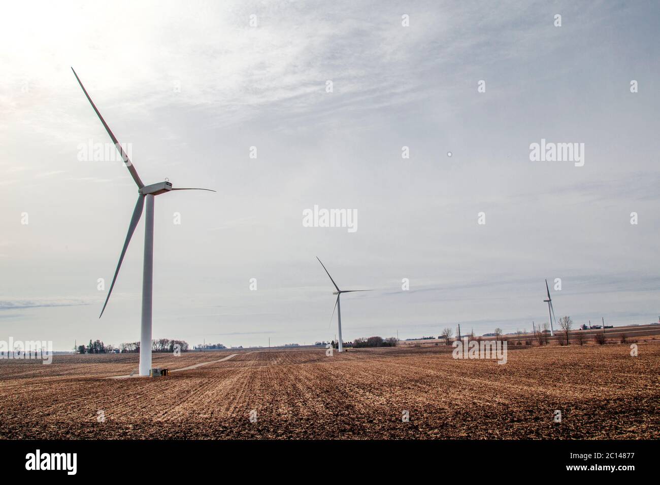 Turbine eoliche su terreni agricoli con cielo sovrastato Foto Stock