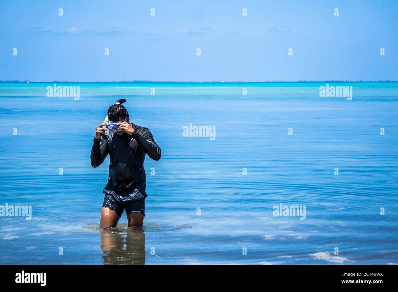 Indiano uomo con attrezzatura da snorkeling che esce d'acqua nelle Maldive Foto Stock