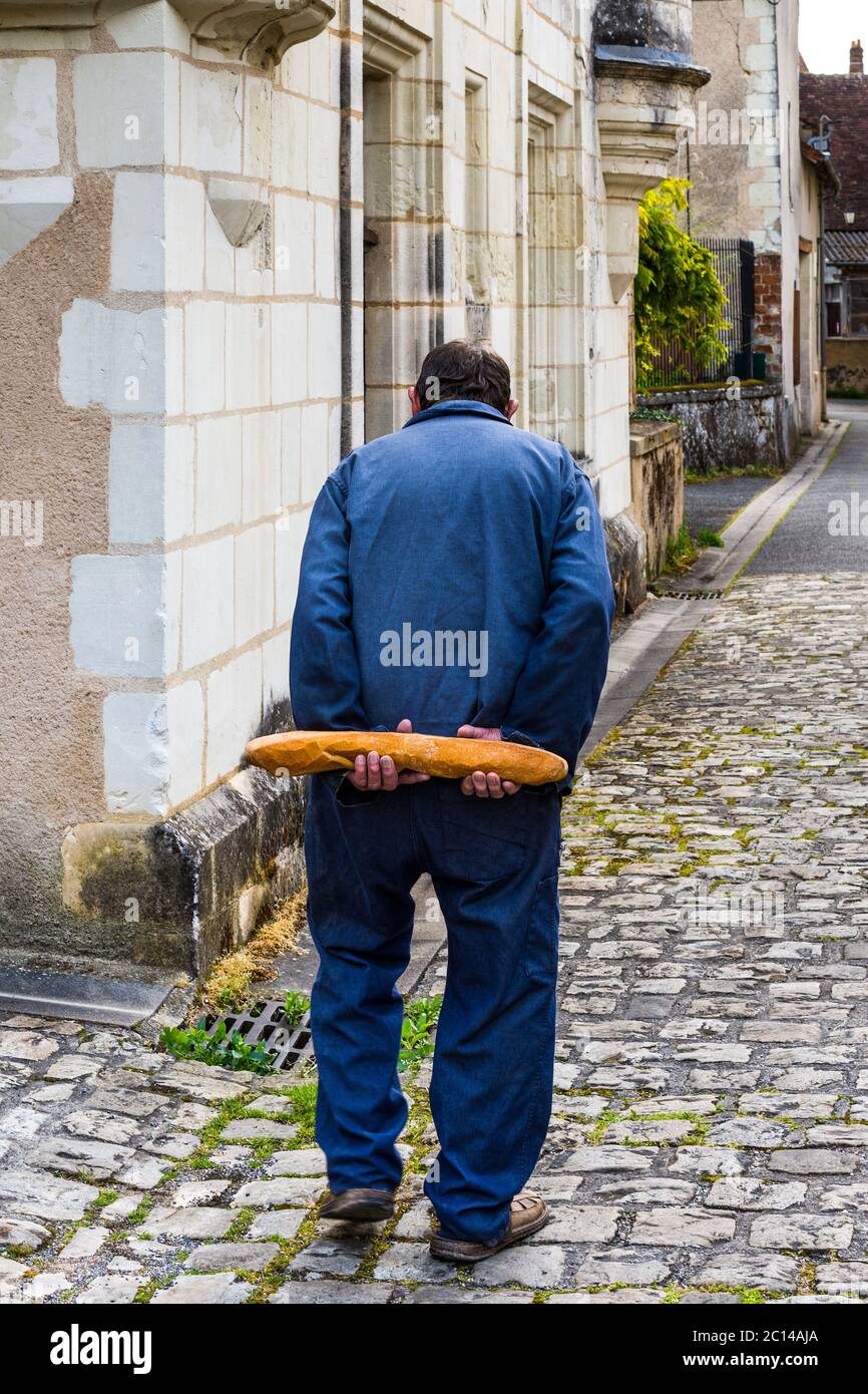 Vecchio francese che cammina a casa tenendo dietro la schiena un pane - Francia. Foto Stock