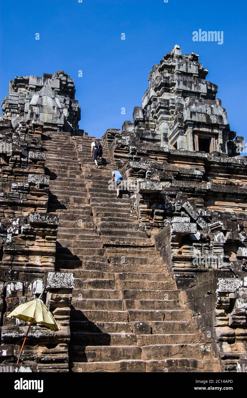 Due turisti arrampicandosi sui gradini ripidi fino alla cima dell'antico tempio Khmer Hindu a Ta Keo, Angkor, Cambogia. Costruito nel 985, la ripida scalinata è de Foto Stock