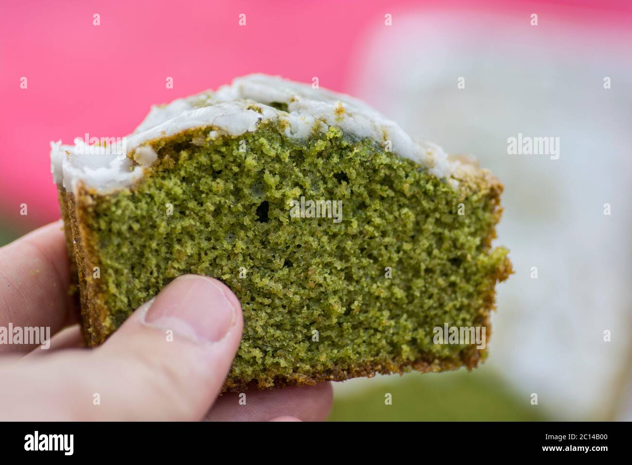 Primo piano di una mano, tenendo una fetta di torta Matcha verde fatta in casa Foto Stock