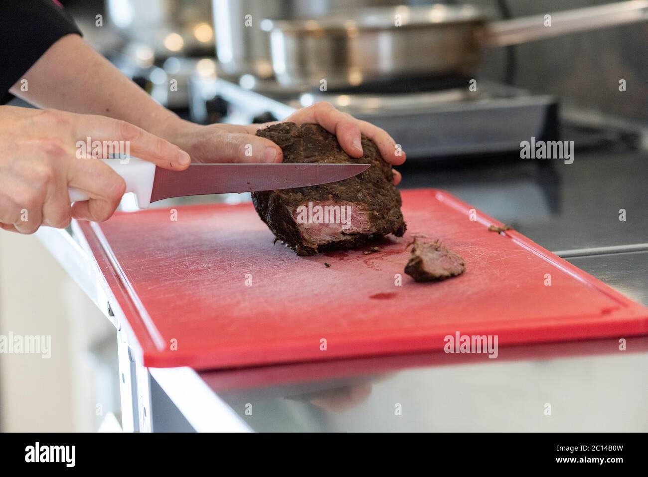 taglio a mano di fette di pastrami sul tagliere facendo una ricetta Foto Stock