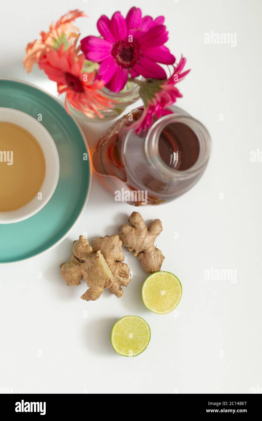 Un colpo di zenzero, una tazza di tè con una bottiglia di gocce di zenzero e un cuneo di limone. Foto Stock