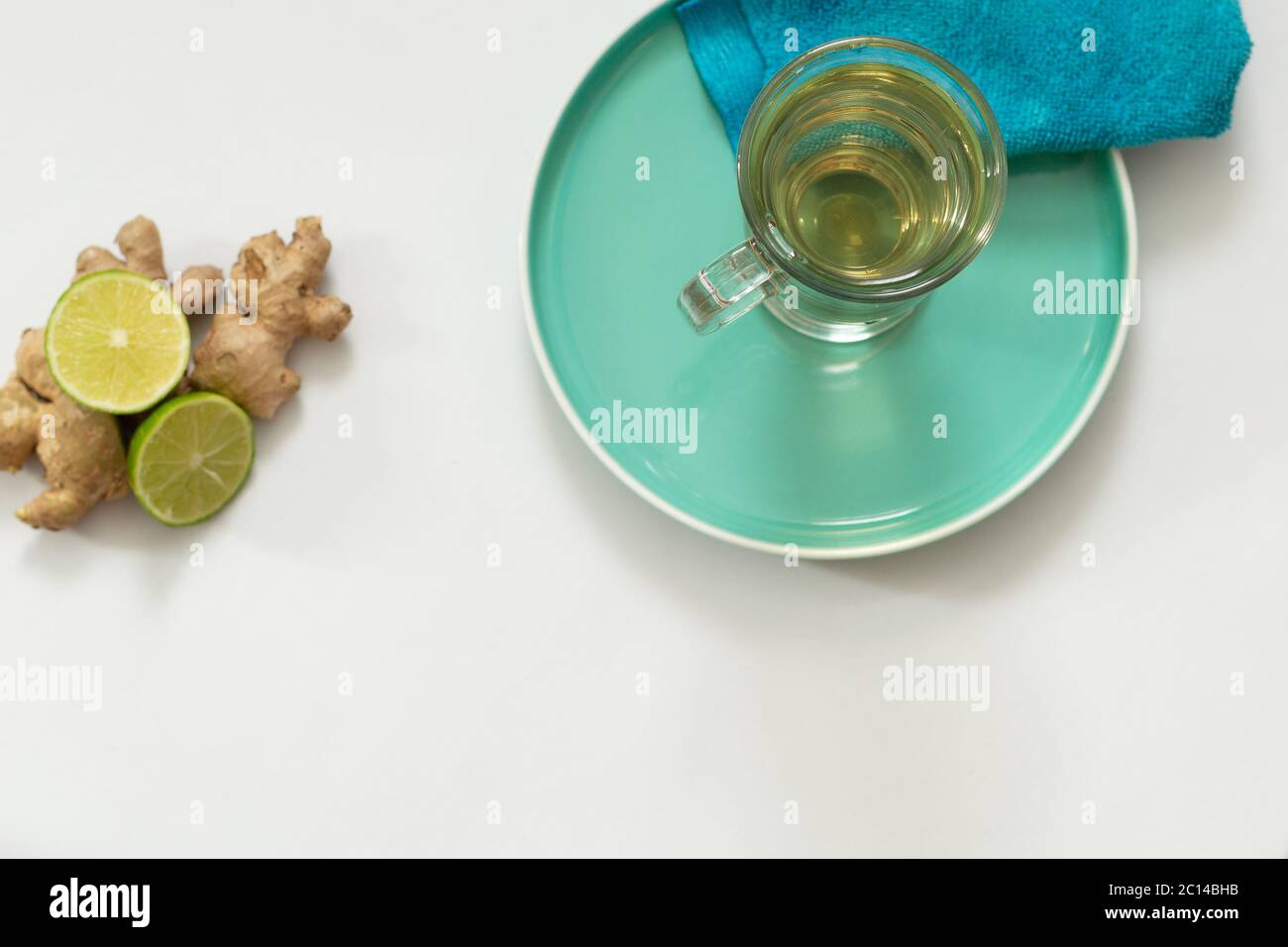 Un colpo di zenzero, una tazza di tè con una bottiglia di gocce di zenzero e un cuneo di limone. Foto Stock