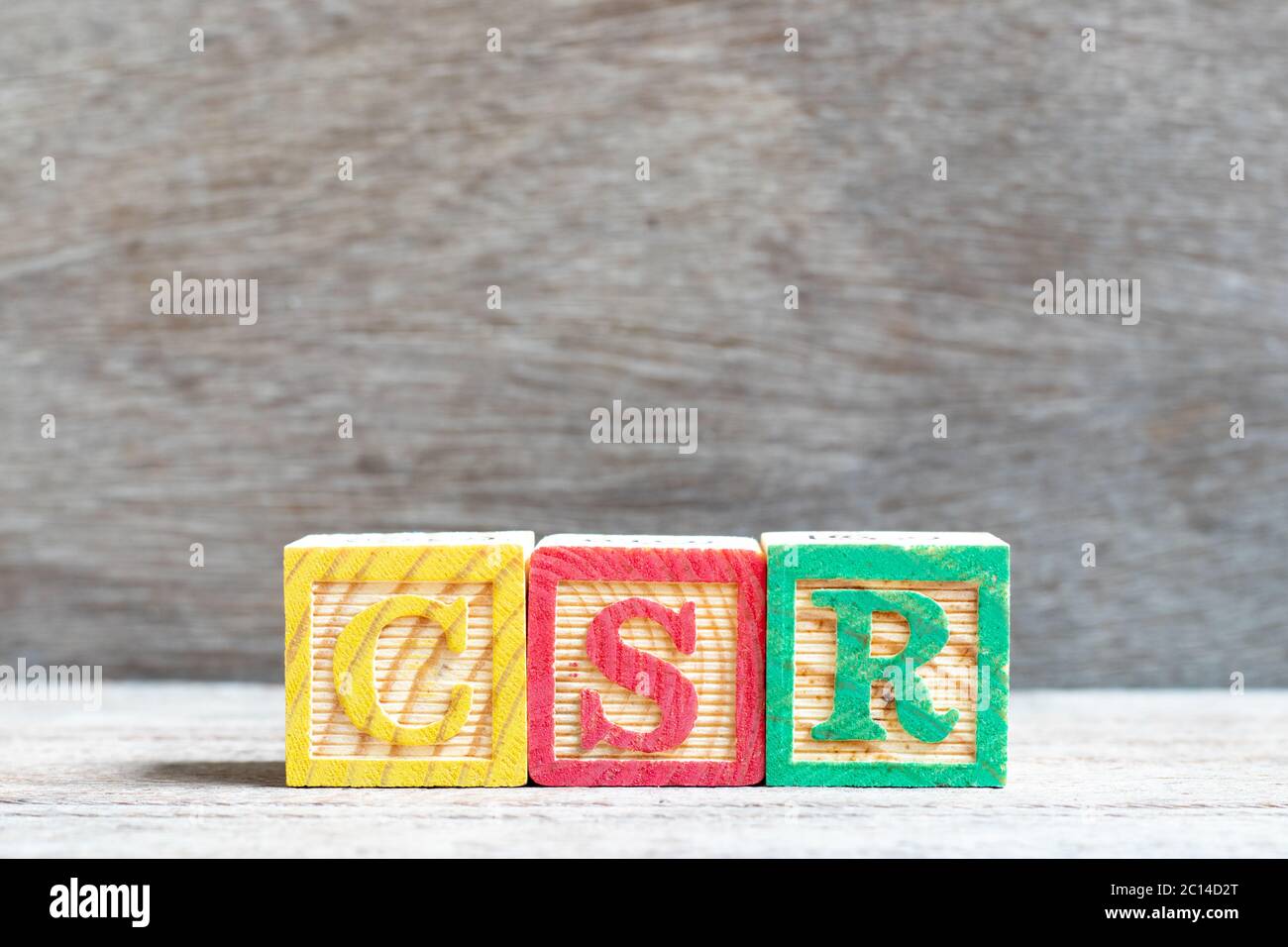 Colore blocco lettera nella parola CSR (abbreviazione di corporate social responsibility) su uno sfondo di legno Foto Stock