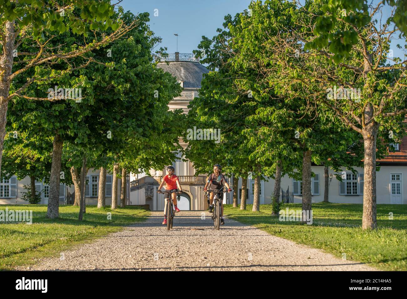 Nonna e nipote in sella alle loro mountain bike e divertirsi in un pomeriggio di sole di fronte al castello di Soliude vicino alla città di Stoccarda Foto Stock